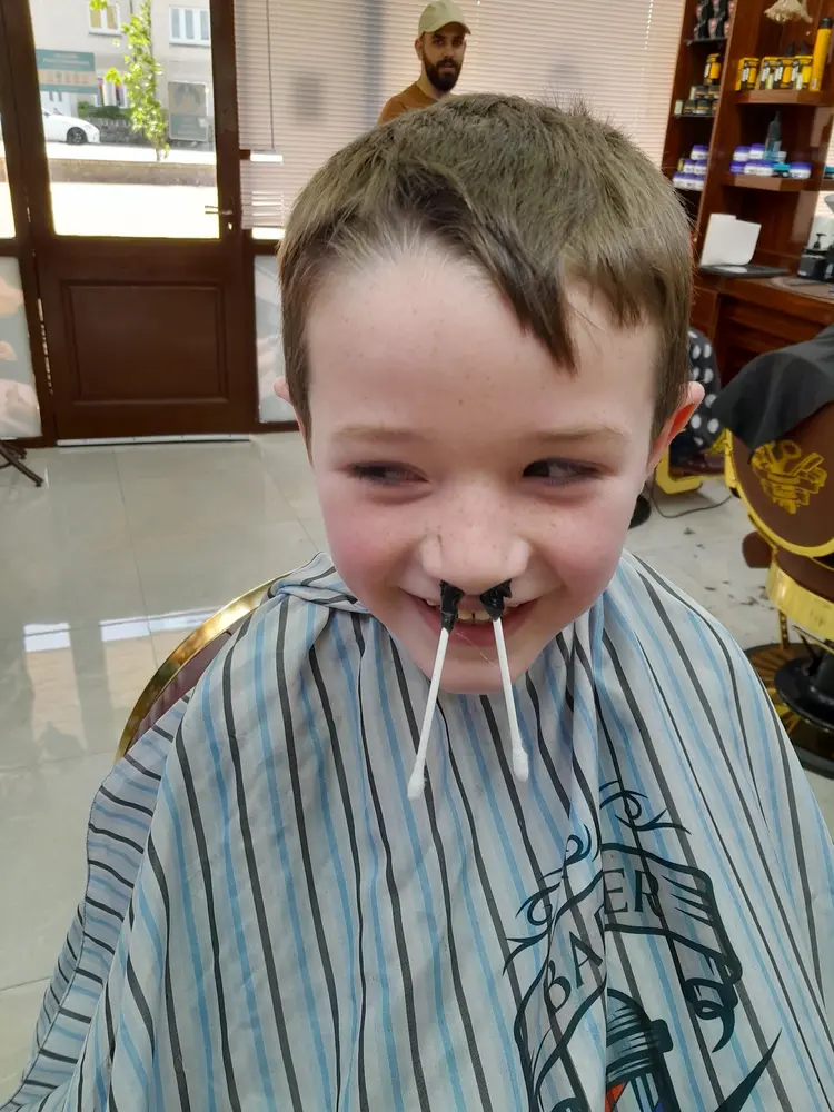 Smiling young client in a striped cape after a nose wax