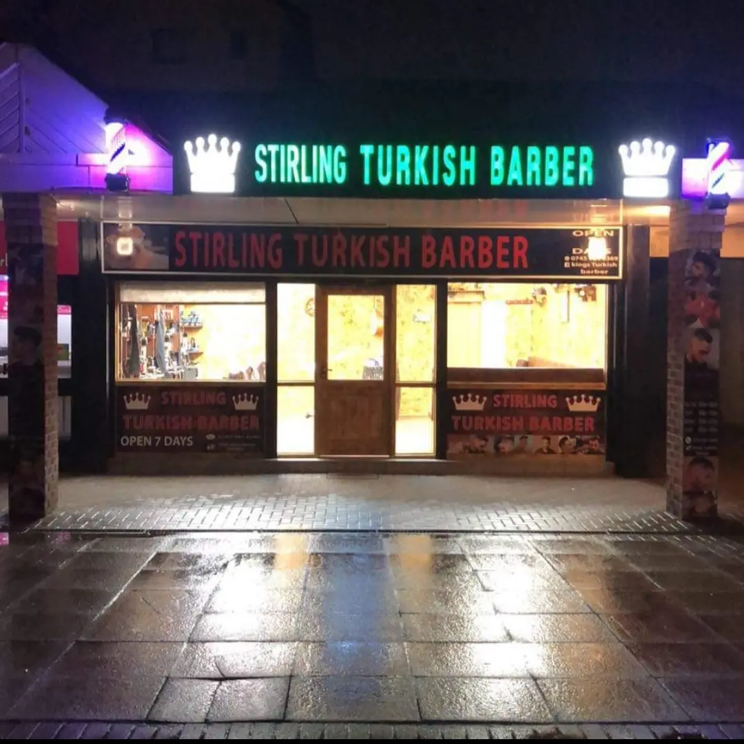 Stirling Turkish Barber shopfront lit up at night, neon crowns either side of the sign